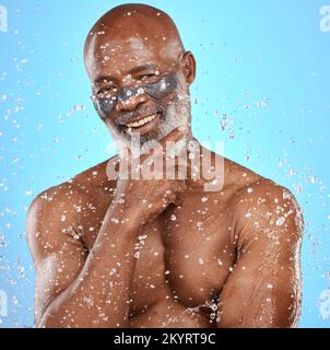 Wasser, Dusche und Hautpflege mit einem schwarzen Model im Studio auf blauem Hintergrund für Hygiene oder Hydratation. Wasserspritzer, nass und schön mit einem Senioren Stockfoto