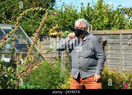 Ältere oder ältere Person trägt eine Maske, um zu verhindern, dass sich ein Virus ähnlich wie Covid ansteckt oder weitergibt. Stockfoto