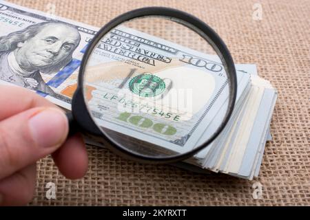 Lupe wird über die Banknote Bündel von US-Dollar gehalten. Stockfoto
