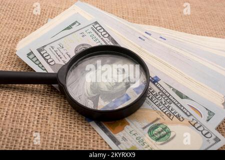 Lupe wird über die Banknote Bündel von US-Dollar gehalten. Stockfoto