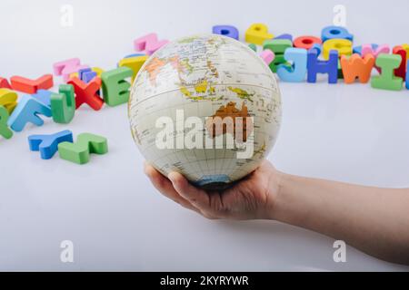 Kleines Modell gobe in Hand mit bunten Buchstaben hinter Stockfoto