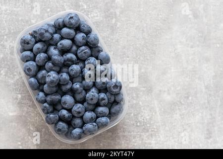 Frische Blaubeere in einer Kunststoffbox auf weißem Hintergrund. Platz für Text. Stockfoto