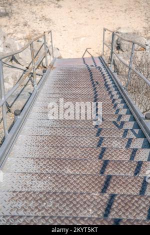 Außentreppe vor trockenem, sonnenbeleuchtetem Boden in der Nähe des Lake Austin in Texas. Von einer öffentlichen Treppe mit dreckigen Metalltreppen und rostigem Zustand nach unten blicken Stockfoto