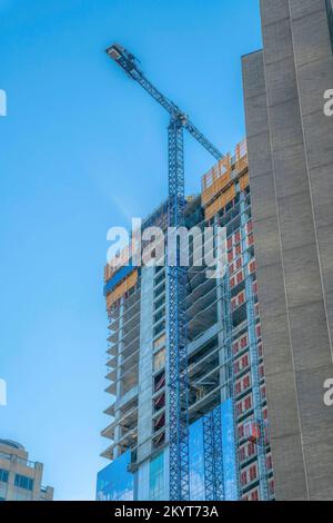 Baukran vor einem unvollendeten Gebäude in der Innenstadt von Austin Texas. Apartment oder Büroeinheit wird gebaut mit Blick auf die klare Wolke Stockfoto