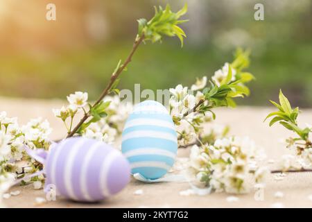 Frohe Ostern. Ostereier auf einem rustikalen Tisch mit Kirschblüten. Natürlich gefärbte bunte Eier und Frühlingsblumen. Landleben Stockfoto