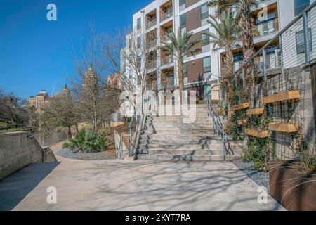 Der Weg in San Antonio Texas führt zu einer Treppe, die einen Gebäudeeingang hinaufführt. Der Wanderweg führt auch zu einer malerischen Landschaft mit Fluss und Bauwerk Stockfoto