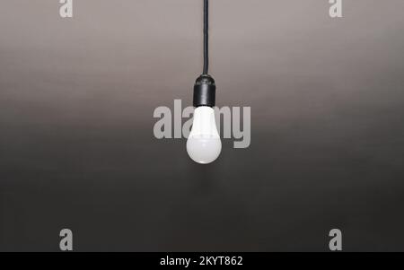 Eine Lampe, die an einem Kabel hängt. Einsame LED-Lampe. Stockfoto