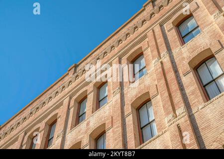 Außenansicht des Gebäudes mit rechteckigen Fenstern und Backsteinwänden vor blauem Himmel. Blick auf die Apartments und Residenzen von der Straße in San Antonio Texas Stockfoto