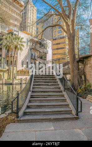 Treppen auf ein Gebäude mit Blick auf den Kanal im San Antonio River Walk Texas. Wunderschöne Landschaft einer beliebten Touristenattraktion mit den Gebäuden A. Stockfoto