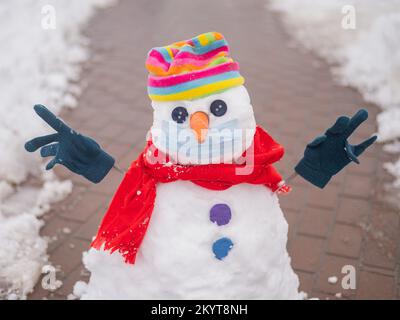 Schneemann in einem Regenbogenhut und einer medizinischen Maske. Stockfoto