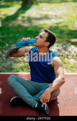 Junger sportlicher Mann macht eine Pause. Trinkwasser Stockfoto