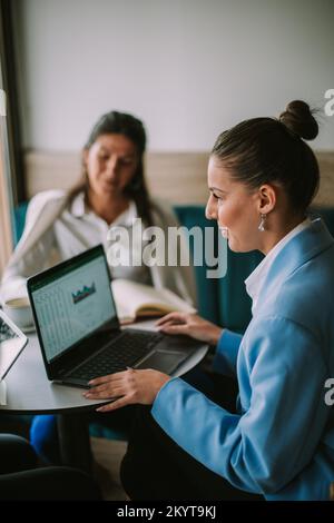 Geschäftsfrau, die am Laptop arbeitet und mit ihren Freunden über ihr neuestes Projekt chattet Stockfoto