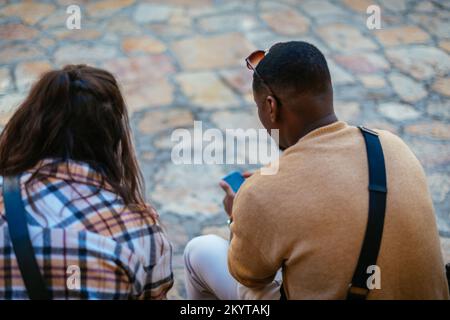 Männliche und weibliche Touristen hingen den ganzen Tag in der Stadt herum. Sie sitzen auf einer Bank und machen eine Pause Stockfoto