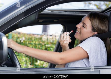 Frau setzen auf Lippenstift in einem Auto Stockfoto