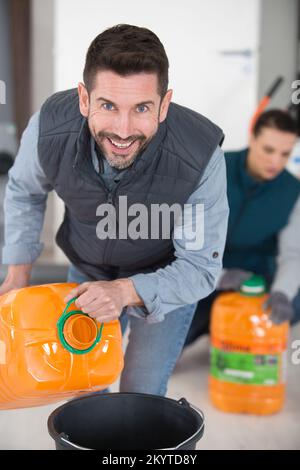 Mann, der das Altöl in den grünen Tank gießt Stockfoto