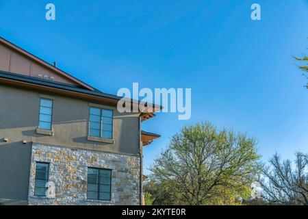 Austin, Texas - Außenansicht eines Hauses in der Nähe des Lake Austin vor dem Hintergrund des blauen Himmels. Wohnaußenseite mit Steinfurnier Wandverkleidung und grau gestrichen Stockfoto