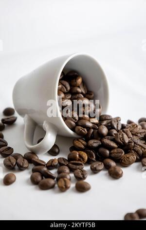 Verschüttete Kaffeebohnen aus einer Tasse. Weißer Hintergrund. Stockfoto