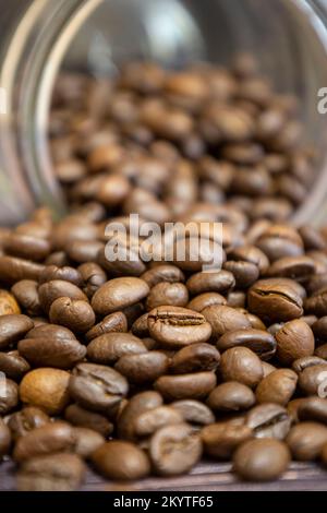 Kaffeebohnen aus einem Glasgefäß verschüttet. Selektiver Fokus. Stockfoto