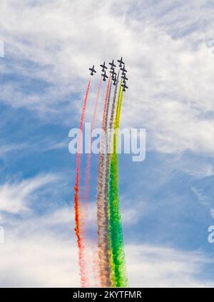 Flugshow des Aerobatikteams Frecce Tricolori der Italienischen Luftwaffe mit bunten Rauchpfaden vor teilweise bewölktem Himmel Stockfoto