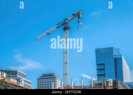 Austin, Texas - hoher Turmkran mit hängenden US-Flaggen über dem Unterbaugebäude. Im Bau, mitten in einem Hochhaus Stockfoto