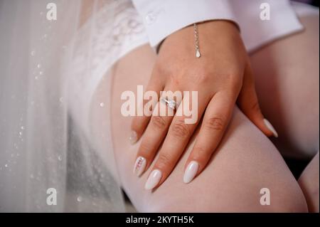 Goldring mit einem Diamanten an der Hand der Braut. Ring mit einem Stein an der Hand einer Frau. Stockfoto