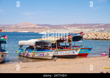 Die Boote fuhren am Al-Ghandour Beach in Aqaba Jordan und blickten auf die Hügel von Isreal und Ägypten Stockfoto