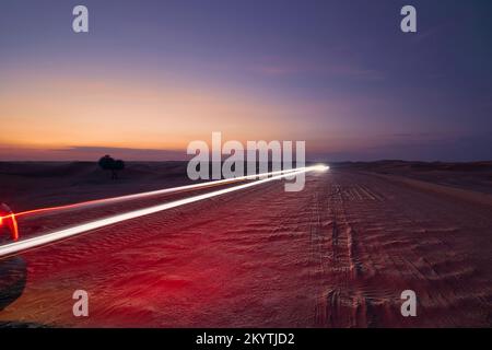 Leichte Autowege auf der Wüstenstraße in den mittleren Sanddünen. Abu Dhabi, Vereinigte Arabische Emirate Stockfoto