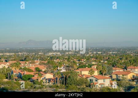 Phoenix, Arizona - Blick auf die Häuser vom Pima Canyon Wanderweg. Unterteilungshäuser mit Palmen und Wüstenpflanzen im Freien gegen schwache Sicht auf Stockfoto