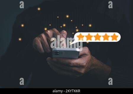Geschäftskonzept. Der Kunde drückt mit der Hand auf den Smartphone-Bildschirm mit einem goldenen fünf-Sterne-Bewertungssymbol und drückt die Stufe ausgezeichnet, um B zu geben Stockfoto