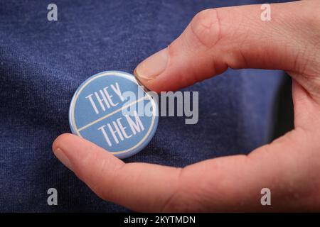 Eine Person, die ihre Pronomen zeigt, indem sie eine Marke trägt. Stockfoto