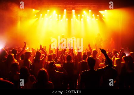 Rock Hands, Konzert und Musikfestival mit roten Disco-Lichtern für Energie, Dunkelheit und psychedelischen Tanz, Feier und Party. Band, Musiker Stockfoto