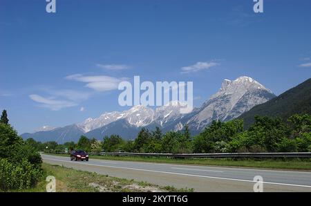 Dettingen an der Iller, Baden-Württemberg: Ein Auto fährt auf einer deutschen Autobahn mit den Alpen im Hintergrund. Stockfoto