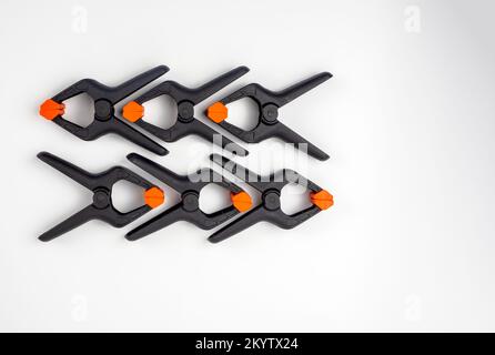 Sechs schwarze Kunststoff-Foto- und Holzbearbeitungsklemmen, isoliert auf weißem Hintergrund Stockfoto