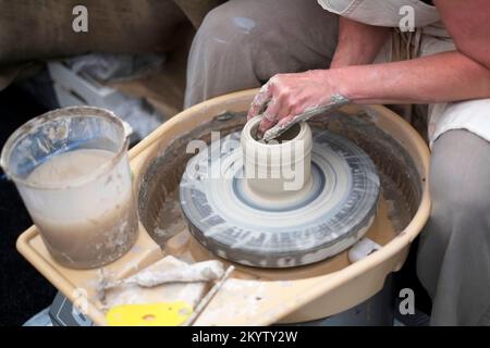 Potter saß rechts vom drehenden Töpferrad und machte Tontopf Stockfoto