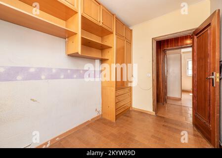 Zimmer mit alten verfallenen Möbeln und Steinzeug-Fußböden verschiedener Modelle und rötlichen Holztüren Stockfoto