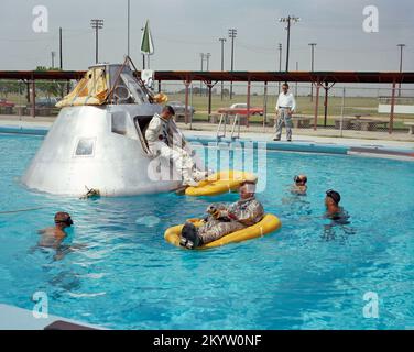 Übung zum Wasserausstieg mit der Apollo 1 Prime Crew - Mitglieder der Ellington AFB, TX Prime Crew wurden von der National Aeronautics and Space Administration (NASA) für die erste Besatzung der Apollo 1 Raumflugübung angekündigt. Wasserausstieg in einem Schwimmbad am Ellington Air Force Base (EAFB), Houston, Texas. Astronaut Edward H. White II. Fährt Rettungsfloß im Vordergrund. Astronaut Roger B. Chaffee sitzt in der Luke des Boilerplate-Modells des Raumschiffs. Astronaut Virgil I. Grissom, drittes Crewmitglied, wartet im Raumschiff. Stockfoto