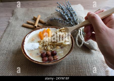 Traditionelles türkisches Dessert Ashura. Walnüsse, Mandeln, getrocknete Aprikosen, Haselnüsse, Zimtstangen, Nahaufnahme. Stockfoto