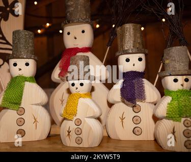 Umweltfreundliche Schneemänner aus Holz mit bunten Schals stehen auf einem Regal Stockfoto