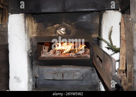 Ein helles Feuer brennt in einem alten Ofen mit offener Metalltür, Kopierraum Stockfoto