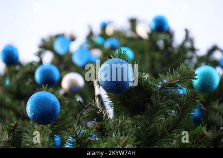 Blaue weihnachtsbälle, die im Winter an Tannenzweigen hängen. Neujahrsbaum mit Dekorationen, Ansicht von unten Stockfoto