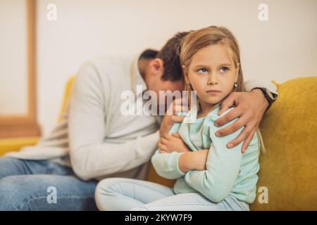 Das kleine Mädchen ist wütend nach einem Konflikt mit ihrem Vater und er versucht, sie zu trösten. Stockfoto