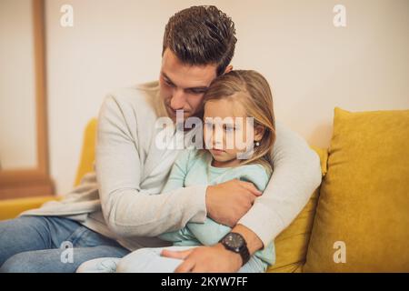 Das kleine Mädchen ist wütend nach einem Konflikt mit ihrem Vater und er versucht, sie zu trösten. Stockfoto