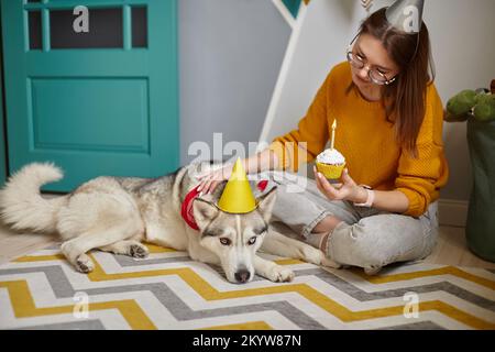 Hundetier Geburtstagsparty, Frau gratulierte traurigem älteren Haustier zum Geburtstag Cupcake Happy Birthday Stockfoto