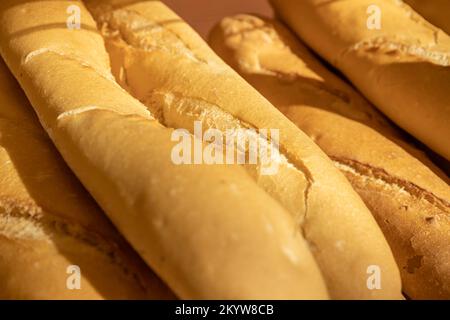 Mehrere Stücke frisch gebackenes französisches Brot. Lebensmittel, die mit raffiniertem Mehl hergestellt werden. Stockfoto