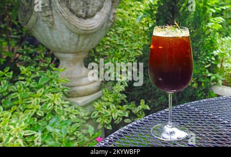Ein Glas Eiskaffee auf dem Gartenteetisch Stockfoto