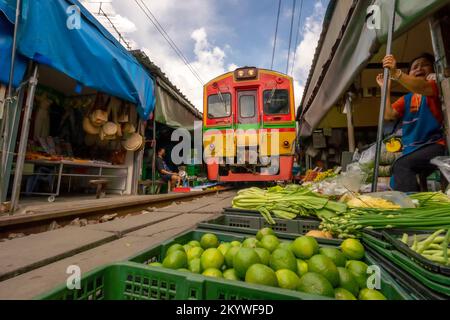 Rom Hoop Schirmmarkt. Thai Railway mit lokalem Zug fährt durch den Mae Klong Markt in der Samut Songkhram Provinz, Thailand. Touristenattraktion in tr Stockfoto