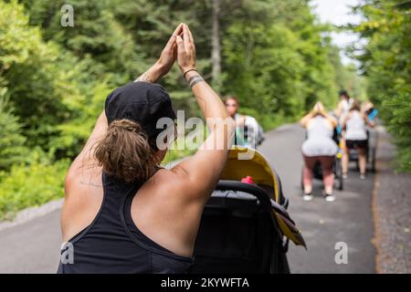 Foto von der Rückseite einer Mutter, die zusammen mit einer Gruppe anderer Mütter Aerobic-Unterricht nimmt, um nach der Geburt ihrer Babys wieder Kraft zu erlangen Stockfoto