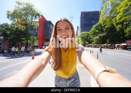 Tourismus in Sao Paulo. Ein wunderschönes lächelndes Mädchen macht Selbstporträts auf der Paulista Avenue, Sao Paulo, Brasilien. Stockfoto