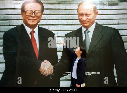 Das neunjährige Mädchen Lili Mok zeigt auf ein riesiges Foto des chinesischen Präsidenten Jiang Zemin, das während seines Chinabesuchs im Jahr 2000 die Hand schüttelte mit dem russischen Präsidenten Wladimir Putin. Die Teil einer Ausstellung wertvoller staatlicher Geschenke ist, die der Volksrepublik China von anderen Ländern überreicht werden. Die Ausstellung beginnt vom 27.. März bis zum 5.. April 2002 im Hong Kong Convention and Exhibition Centre. ***NICHT FÜR WERBEZWECKE*** Stockfoto