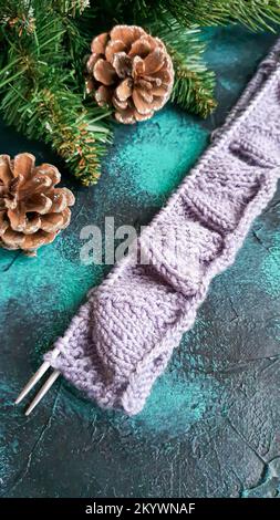 Handgefertigter Pullover. Strickmaterial aus Fliederfaden. Mit weihnachtlichem Hintergrund. Stockfoto